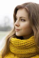 Pretty woman in a yellow knit scarf looks into the distance. Outdoor portrait. photo