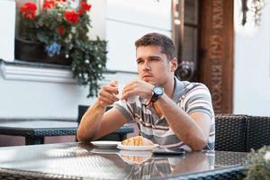 joven bebiendo café con croissant foto