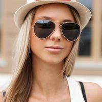 Pretty girl in sunglasses and hat standing at the wall photo