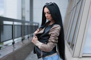 Girl in a leather jacket standing near the building photo