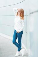 Portrait of beautiful fashionable woman near the modern white metal wall. photo