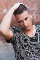 Close-up portrait of a young hipster in a black vintage t-shirt on a background of red bricks. photo