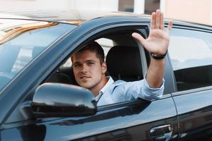 A young man in a car stuck his hand out the window. Man approves photo