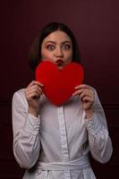 mujer de pelo corto con los ojos y los labios abiertos dando forma a un beso con forma de corazón foto