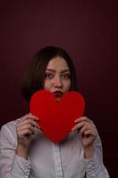 mujer de pelo corto sosteniendo una forma de corazón frente a su barbilla foto