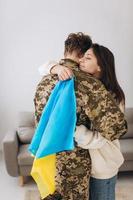 una niña ucraniana abraza y sostiene una bandera amarilla y azul de un militar uniformado y se despide de él. foto