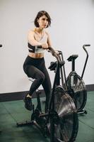 mujer crossfit haciendo entrenamiento cardiovascular intenso en bicicleta de aire foto