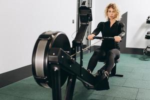 mujer haciendo ejercicio en la máquina de remo, parte de la sesión de cardio de calentamiento de entrenamiento de circuito foto