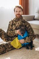 Ukrainian soldier hugging and wrapping his faithful friend's Ukrainian flag around an Amstaff dog in the office photo