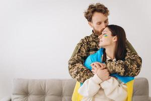 Ukrainian couple, military man in uniform hugs and wraps his wife in the Ukrainian flag. The concept of patriotism. photo