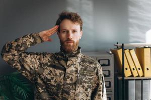 retrato de un soldado ucraniano con uniforme militar rindiendo homenaje en la oficina foto
