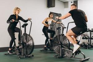 Young man and women using air bike for cardio workout at cross training gym photo