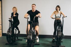 Young man and women using air bike for cardio workout at cross training gym photo
