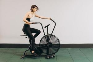 mujer crossfit haciendo entrenamiento cardiovascular intenso en bicicleta de aire foto