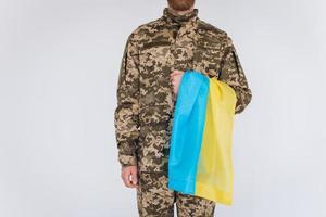 Ukrainian patriot soldier in military uniform holding a yellow and blue flag on a white background photo