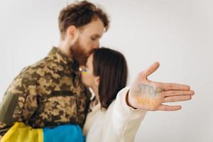 Ukrainian soldier in military uniform with his girlfriend showing a hand with the inscription stop war photo