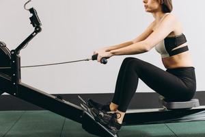 Woman exercising on rowing machine, part of circuit training warmup cardio session photo