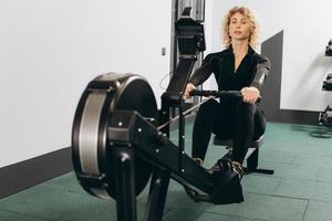 Woman exercising on rowing machine, part of circuit training warmup cardio session photo