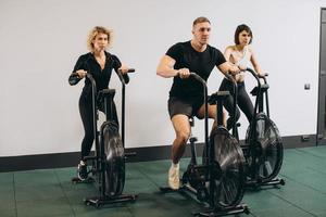 Young man and women using air bike for cardio workout at cross training gym photo