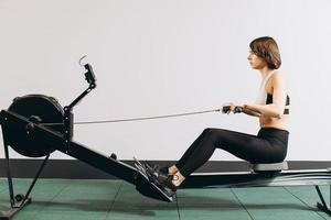 Woman exercising on rowing machine, part of circuit training warmup cardio session photo