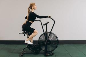 Crossfit woman doing intense cardio training on exercise air bike photo