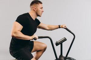 hombre fuerte que usa bicicleta de aire para hacer ejercicio cardiovascular en el gimnasio de entrenamiento cruzado. foto