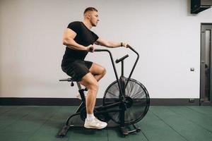 Strong man using air bike for cardio workout at cross training gym. photo