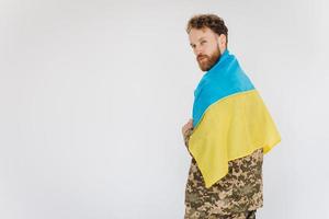 Ukrainian patriot soldier in military uniform holding a yellow and blue flag on a white background photo