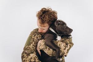 Ukrainian soldier in military uniform holds a dog in his arms on a white background photo