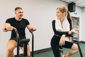 Young man and woman using air bike for cardio workout at cross training gym photo