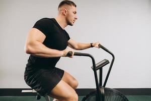 Strong man using air bike for cardio workout at cross training gym. photo