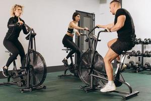 Young man and women using air bike for cardio workout at cross training gym