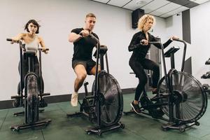 Young man and women using air bike for cardio workout at cross training gym photo