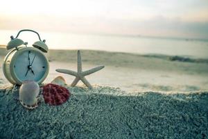 reloj y estrellas de mar en la arena blanca del mar. foto