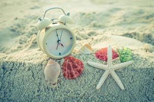 reloj y estrellas de mar en la arena blanca del mar. foto