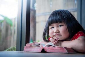 niña lee la biblia y reza en casa, fe pura del niño foto