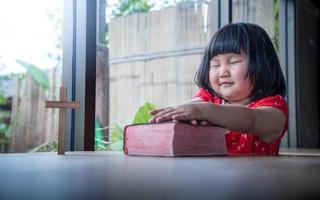 niña rezando en la biblia en casa, fe pura del niño foto