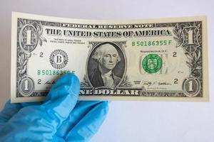 One dollar in a gloved hand on a white background photo