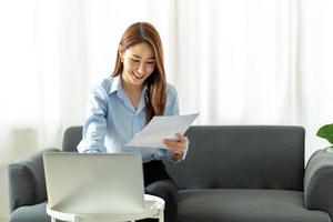 woman using laptop in the sofa with a happy face sitting and smiling with a confident smile. photo