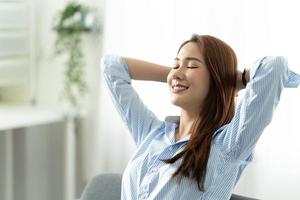 feliz mujer asiática relajándose sentada en un sofá en casa, trabajando desde el concepto de casa. foto