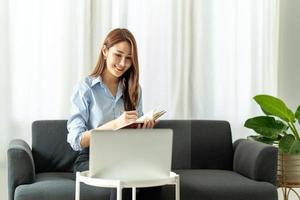 woman using laptop in the sofa with a happy face sitting and smiling with a confident smile. photo