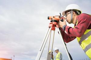 topógrafo ingeniero que trabaja con teodolito en el sitio de construcción foto