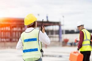 Engineer surveyor using walkie-talkie at construction site photo