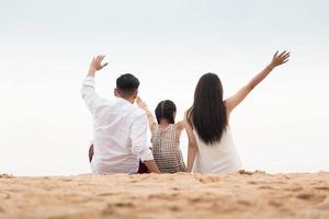 vista trasera de una familia feliz en la playa al atardecer foto