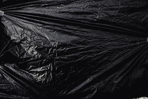 a transparent stretch plastic wrap on black background. realistic plastic wrap texture for overlay and effect. wrinkled plastic pattern for creative and decorative design. photo