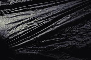 a transparent stretch plastic wrap on black background. realistic plastic wrap texture for overlay and effect. wrinkled plastic pattern for creative and decorative design. photo