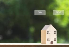 conceptos inmobiliarios, modelo de casa de madera en miniatura con elección de propiedad de compra o alquiler fondo verde borroso. casa ecológica en un entorno verde foto