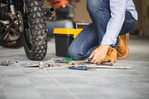 Mechanic fixing motorbike in workshop garage, Man repairing motorcycle in repair shop, Repairing and maintenance concepts photo