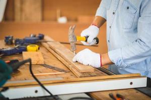Craftsman using hammer hobnailed in workshop, Carpenter using the hammer hit a nail for assembly wood in a carpentry workshop photo