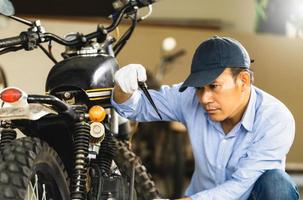 hombre reparando motocicletas en el taller de reparaciones, mecánico reparando motocicletas en el garaje del taller, conceptos de reparación y mantenimiento foto